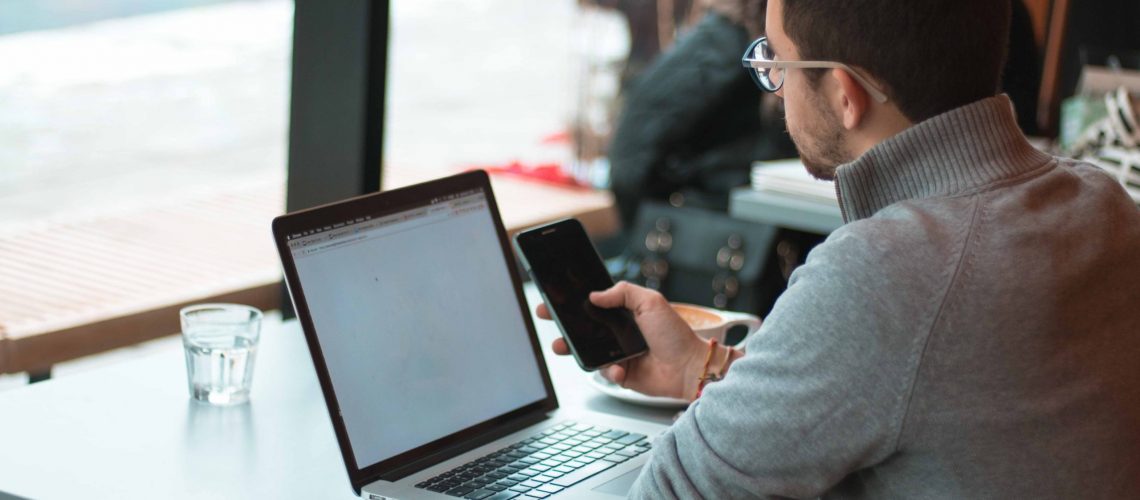 Professional Sitting in a Restaurant Working and Looking at His Phone